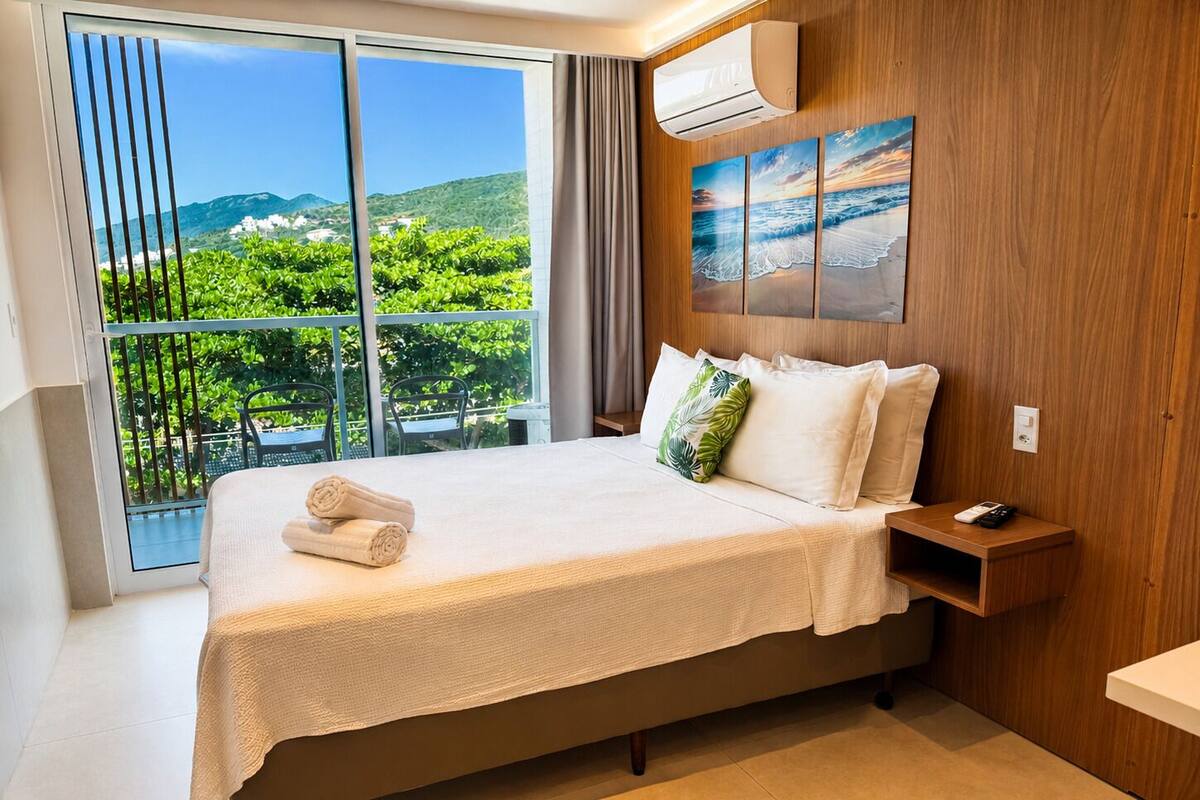 Hotelkamer met een bed, nachtkastje, afstandsbediening en uitzicht op groen en heuvels.