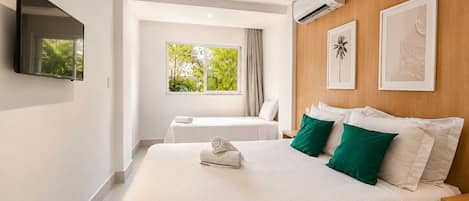Habitación de hotel con una cama grande, una cama más pequeña, televisión, aire acondicionado y ventana con vista a zonas verdes.