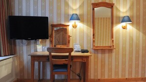 A wooden desk with a chair, a flat-screen TV, two wall-mounted lamps, and a mirror. - Imperial Hotel Rembrandtplein  (Amsterdam)