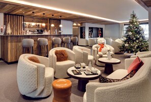 Een moderne lounge met comfortabele zitplaatsen, een bar en een versierde kerstboom.