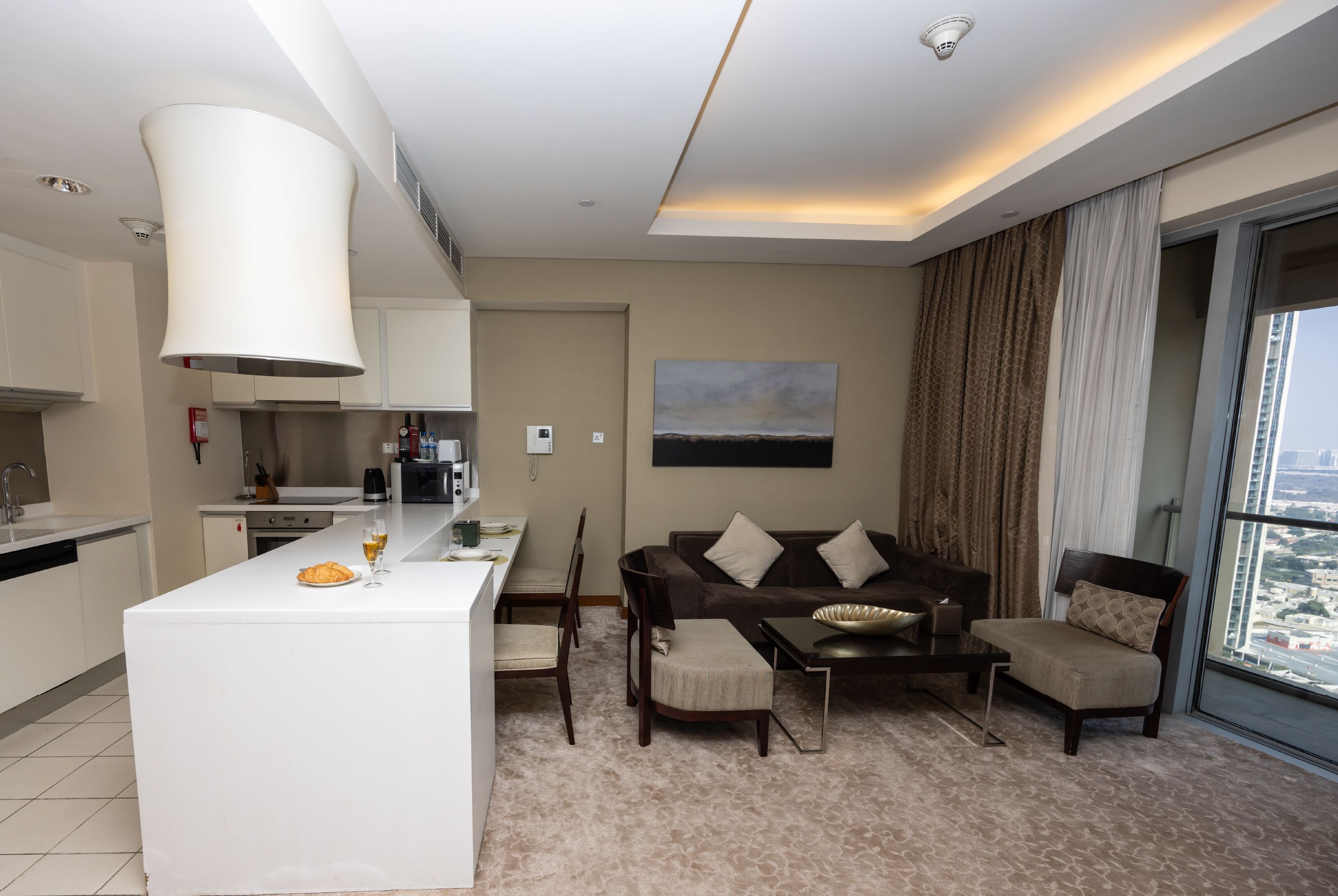 A modern living room with a sofa, chairs, a coffee table, and a kitchen area with a dining table.