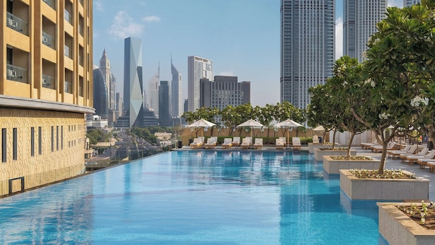 A rooftop infinity pool with lounge chairs and umbrellas, surrounded by high-rise buildings. - Paradise View Holiday Homes L.L.C. (Dubai)