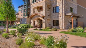 A multi-story building with stone facade, balconies, and a landscaped garden with various plants and flowers. - Constellation #404 Ski-in & Out @ Northstar (Truckee)