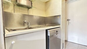 Ett kompakt kök med en diskho i rostfritt stål, en diskmaskin och en mikrovågsugn placerad på bänkskivan.