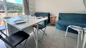 Ett modernt rum med ett matbord, stolar, en soffa och ett litet sidobord.