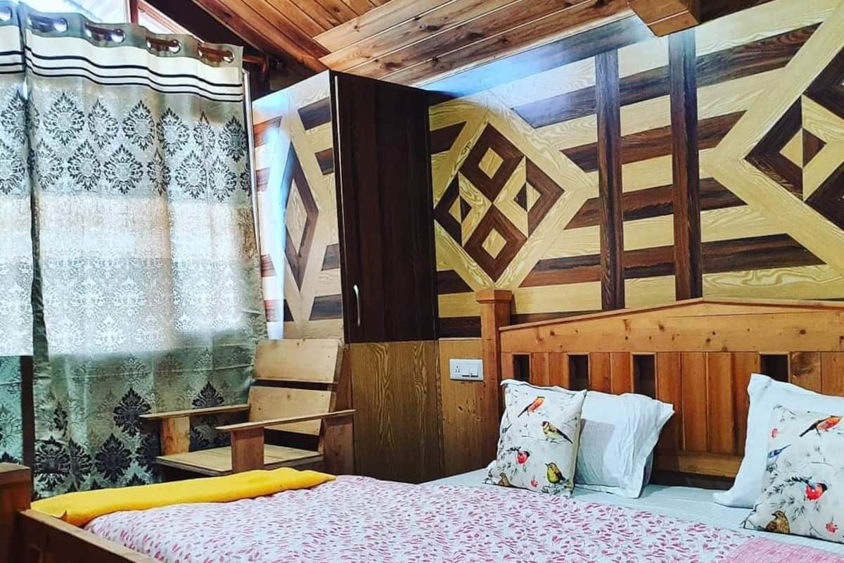 A wooden bed with a patterned bedspread, a wooden headboard, and a nightstand with a lamp.