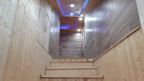 Una escalera de madera que conduce a una habitación con techo inclinado e iluminación empotrada.