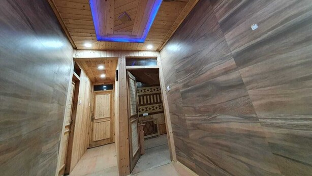 Un pasillo con paredes y techo de madera, una puerta de madera y un papel tapiz con diseño a la derecha.