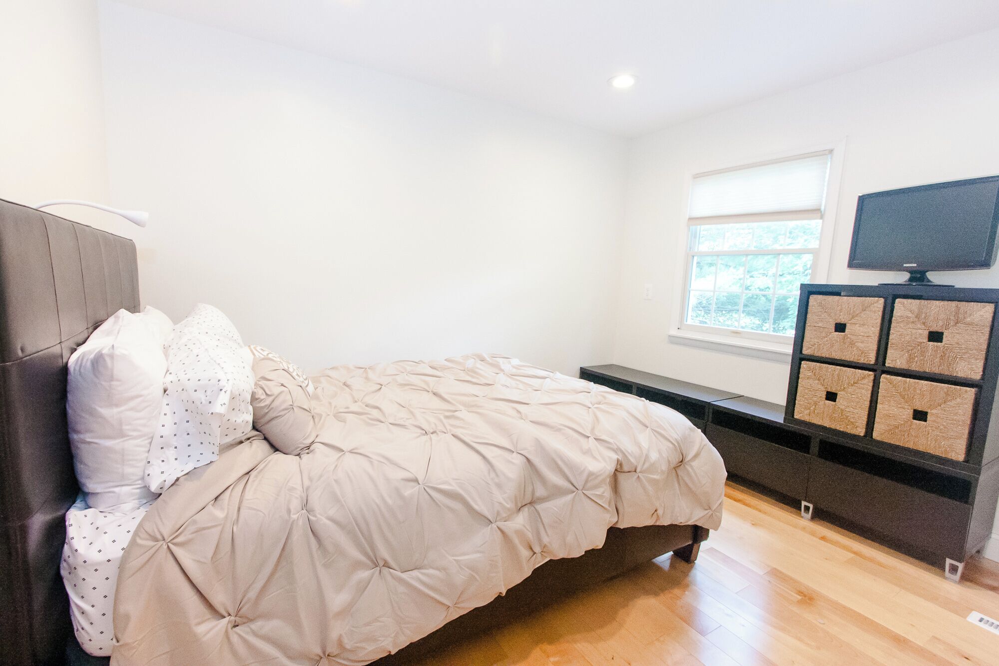 Une chambre à coucher comprenant un lit, une télévision, une fenêtre et un meuble de rangement.