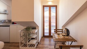 Une cuisine compacte comprenant un coin repas, un petit réfrigérateur et une table en bois avec une bouilloire et des tasses.