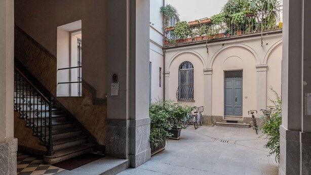 Une cour avec un escalier, des plantes en pot et un vélo.