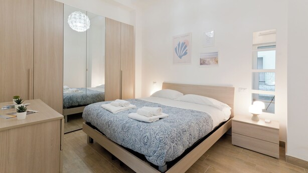 Ein modernes Schlafzimmer mit Bett, Nachttischen, Schreibtisch und Spiegel.