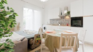 Eine helle, moderne Küche mit weißen Schränken, einem Backofen und einem Fenster mit Blick auf den Garten.