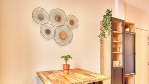 Une table en bois sur laquelle est posée une plante en pot, un élément décoratif fixé au mur et un meuble en bois doté d’étagères.
