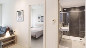 A modern hotel room with a bed, bedside table, and a shower area. - Isaresidence three-room apartment Prestige Suite for 4 persons (Isolaverde di Chioggia)