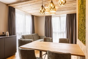 A modern dining area with a wooden table and chairs, a sofa, and a kitchen area with a kettle. - Cosy Apartment in Fugen (Fuegen)