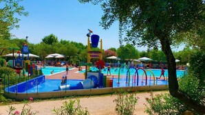 Zona de piscina con múltiples carriles, un tobogán y sillas de descanso.