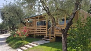 Une cabane en bois avec un escalier menant à une terrasse, entourée de verdure et d’arbres.