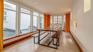 Une pièce spacieuse avec de grandes fenêtres, une table en bois et des bancs.