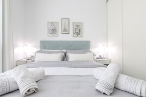 A neatly made bed with striped bedding, a light blue headboard, and three framed artworks on the wall. - La Cala beach apartment (La Cala de Mijas)
