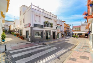 A street view with a building labeled 'Coco' featuring a salon, a crosswalk, and a sidewalk with potted plants. - La Cala beach apartment (La Cala de Mijas)