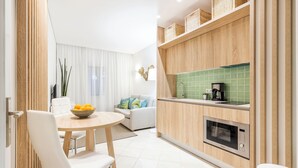 Une cuisine moderne avec des meubles en bois, un four à micro-ondes encastré et un coin repas comprenant une table ronde et des chaises blanches.