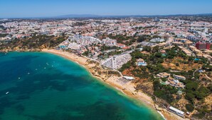 Vue aérienne d’une ville côtière avec une plage, des bâtiments et une eau d’un bleu limpide.
