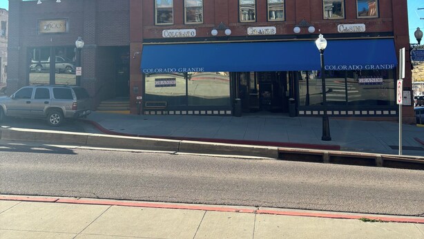 A two-story brick building with a blue awning and a sign reading "Colorado Grande." - Colorado Grande Casino (Cripple Creek)