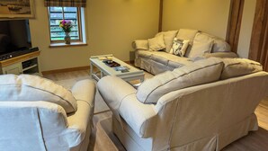 Una sala de estar con sofá, sillones, una mesa de centro y televisor.