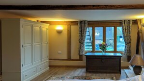 Un dormitorio con una cama grande, un aparador, una ventana con cortinas y una lámpara.