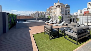 Une terrasse sur le toit avec une piscine, des chaises longues et une plateforme en bois.