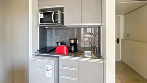 Une cuisine compacte équipée d’un four à micro-ondes, d’un grille-pain, d’une machine à café et d’un réfrigérateur.