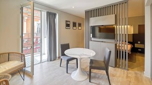 Une chambre d’hôtel moderne dotée d’un coin repas, d’une télévision et d’un balcon offrant une vue sur la ville.