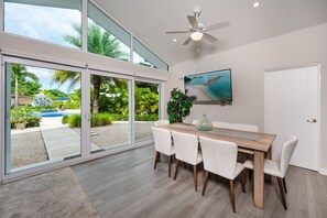 A modern dining area with a large table and chairs, a ceiling fan, and a TV on the wall. - The Point Avellanas - Villa 21 (Playa Avellana)