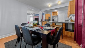 Un coin repas avec une table dressée pour quatre personnes, une cuisine équipée d’appareils électroménagers modernes et un ventilateur de plafond.