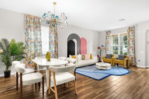 Ein modernes Wohnzimmer mit einem runden Esstisch, Sofas und einem dekorativen Wandbild.