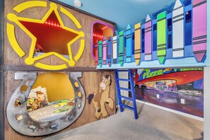 A children's play area with a star-shaped light, a horse sculpture, and a colorful train set.