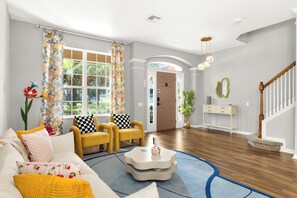 A living room with a sofa, two armchairs, a coffee table, and a staircase.