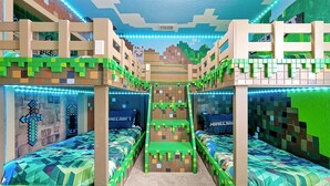 Huoneessa on kerrossängyt, ja jokaisessa sängyssä on Minecraft-teemalla koristeltu pääty ja jalkopääty.