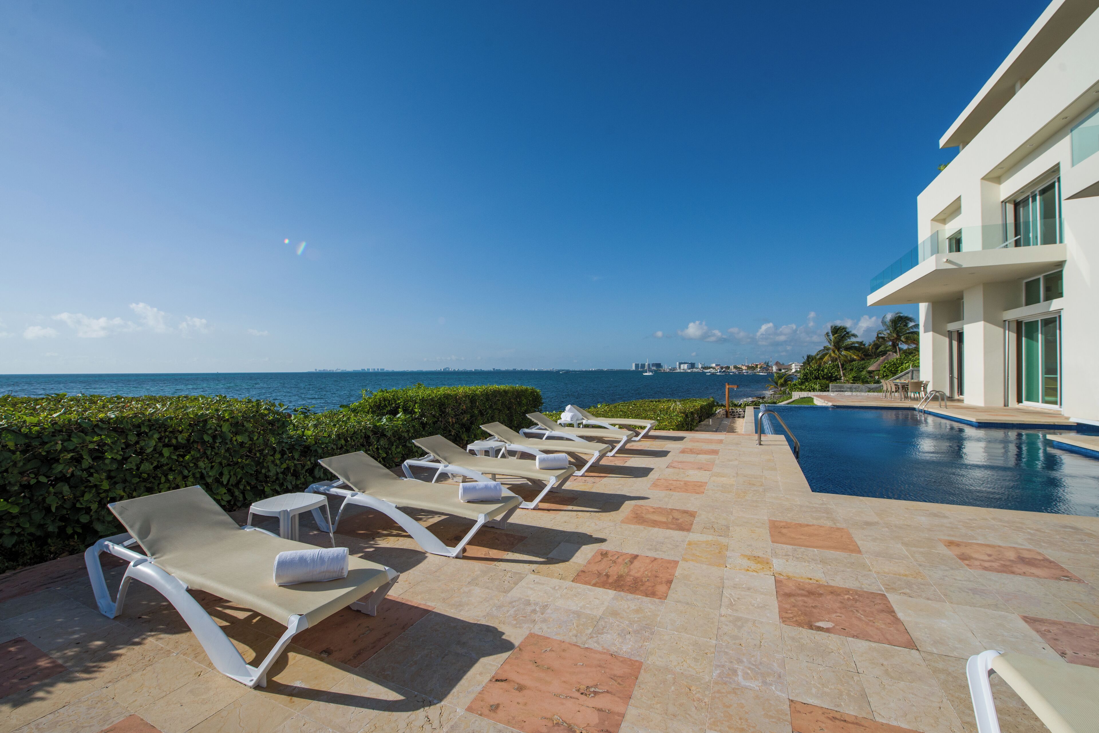 A poolside area with lounge chairs and a view of the ocean.