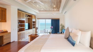 A modern hotel room with a large bed, a desk, and a view of the sea. - Villa Punta Sam Cancun Beachfront Luxury (Cancun)