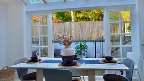 A conservatory with a dining table set for two, surrounded by white walls and large windows.