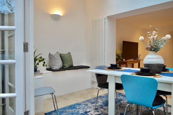 A modern dining area with a white table, blue chairs, and a vase with flowers.