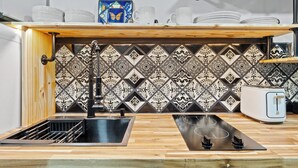 A kitchen with a wooden countertop, a black sink, a patterned backsplash, and a white toaster. - Casita Talavera (Nashville)