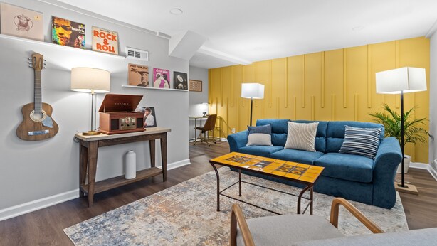 A living room with a blue sofa, wooden coffee table, and a guitar on the wall. - Casita Talavera (Nashville)