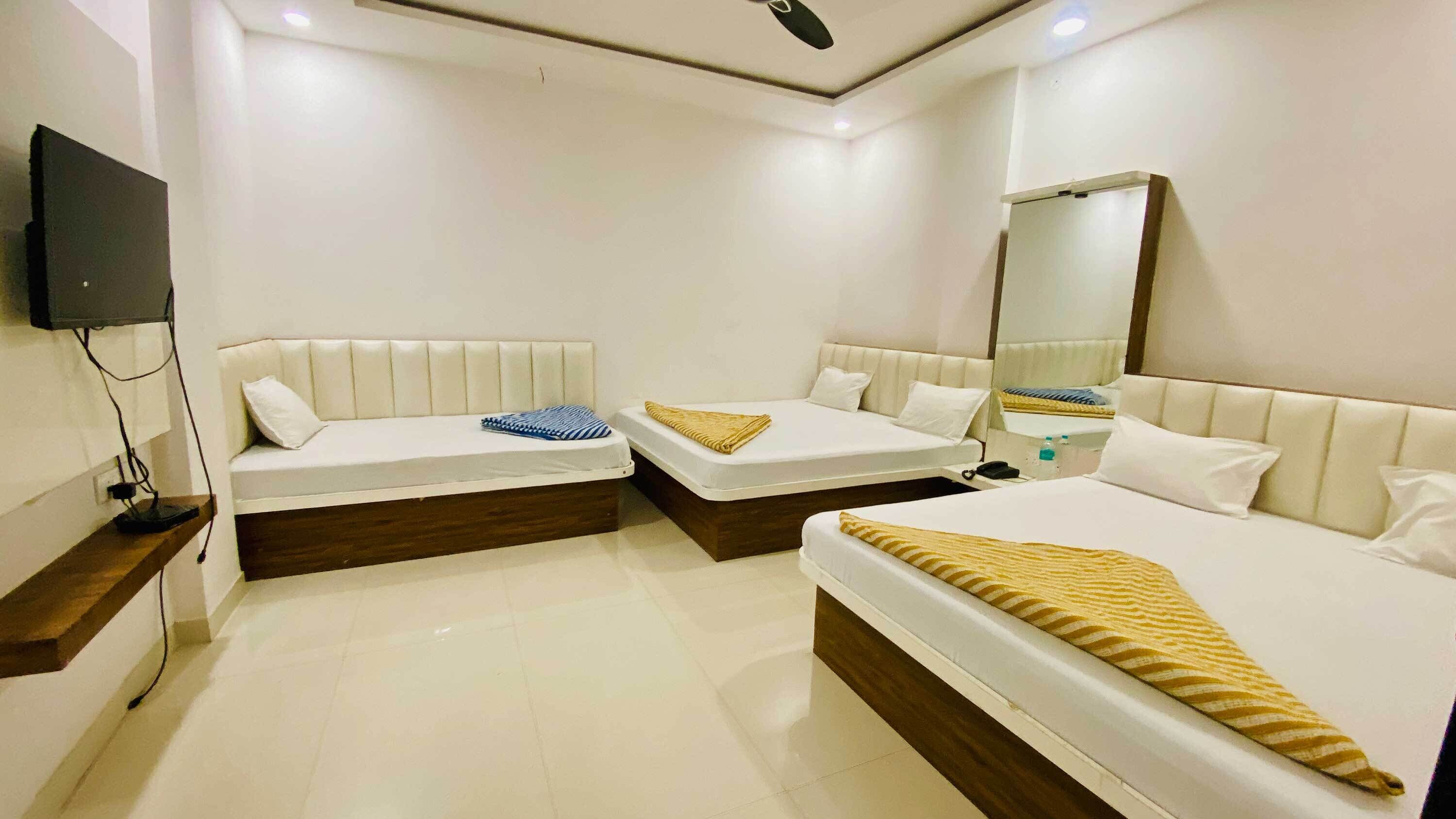 A hotel room with two beds, a flat-screen TV mounted on the wall, and a mirror.