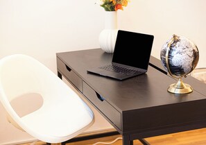 A workspace with a laptop, a globe, and a white chair. - Next'House - Business Boulevard Hostel (Dubai)