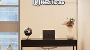 A reception desk with a laptop, a globe, and a vase of flowers. - Next'House - Business Boulevard Hostel (Dubai)