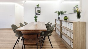 A modern meeting room with a wooden table, green upholstered chairs, a whiteboard, and storage cabinets. - Next'House - Business Boulevard Hostel (Dubai)