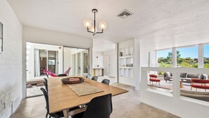 Un'elegante zona pranzo moderna con tavolo in legno, sedie nere e un lampadario.